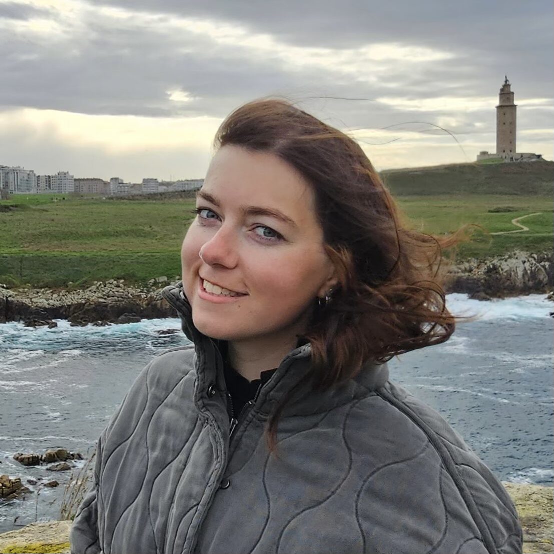 Closeup of ADC Intern Autumn Welling smiling in front of a scenic river and tower.