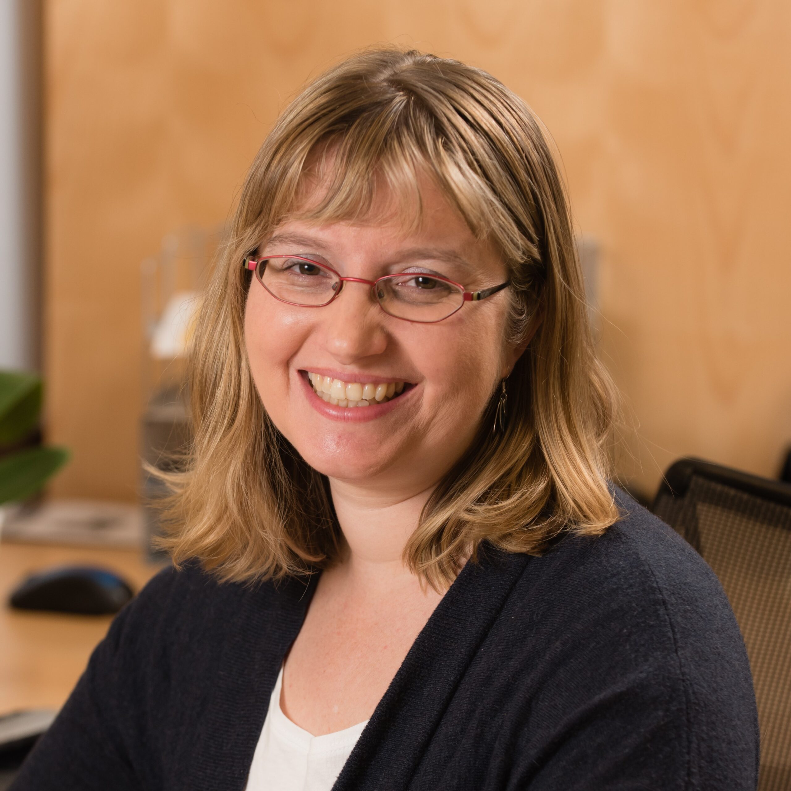 Closeup of ADC Project Manager Emily Coleman-Wolf smiling and sitting at a desk.